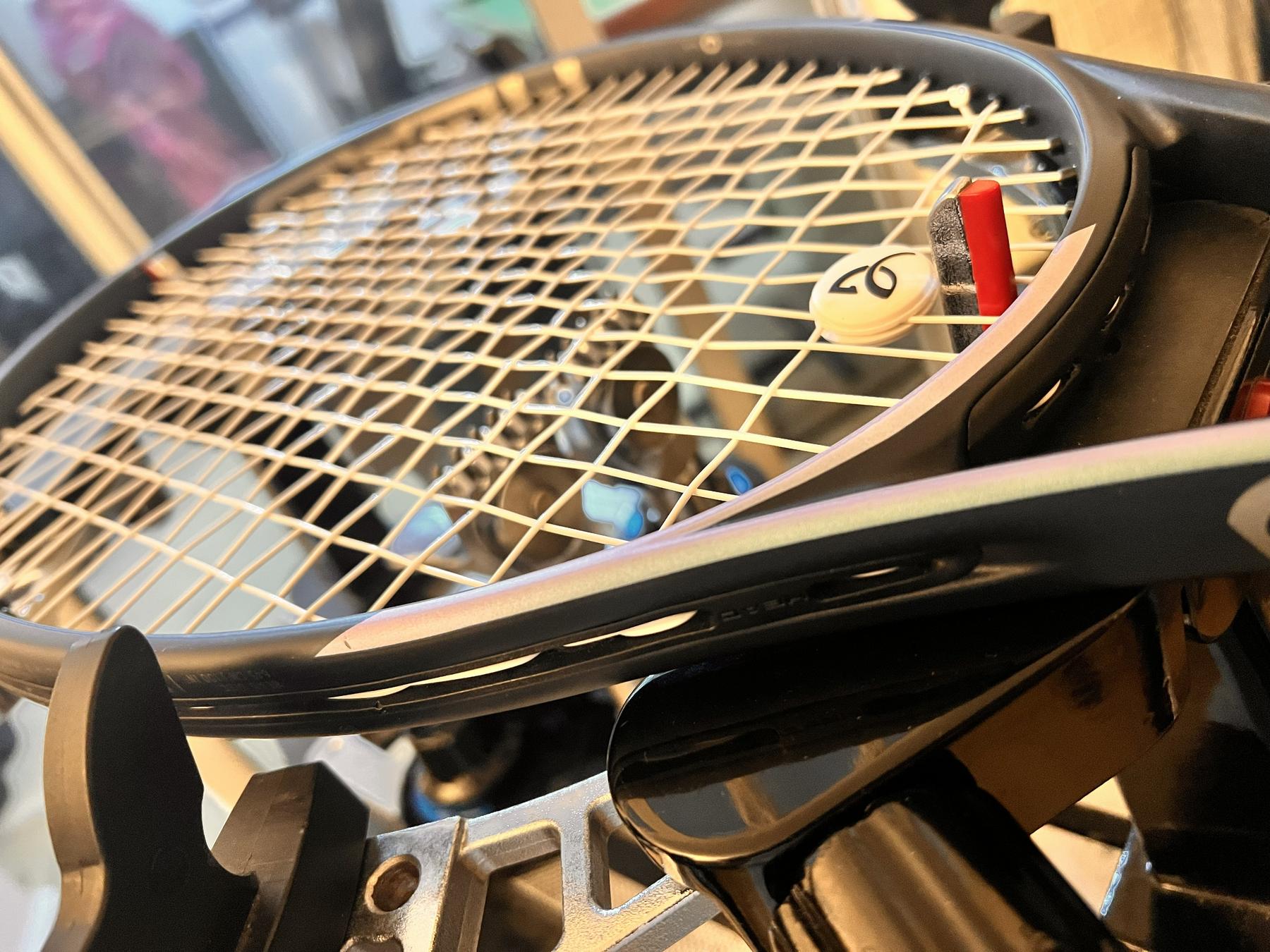 A racket clamped on the ML.stringing machine, freshly strung