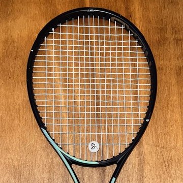 Freshly strung Head tennis racket on a wooden table